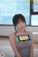 A woman sitting on a bed holding a Nintendo Switch.